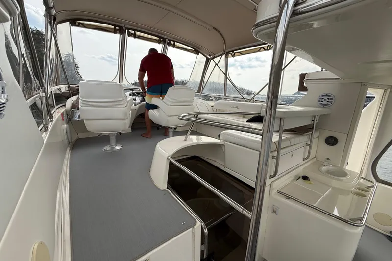 Slide: The Image of 1996 Sea Ray 420 Aft Cabin interior with seating and helm, featuring a person navigating. - 9