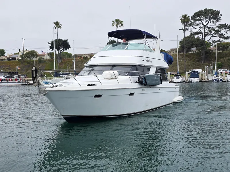Slide: The Image of 2000 Carver 450 Voyager Pilothouse yacht docked in a marina, surrounded by calm waters. - 14