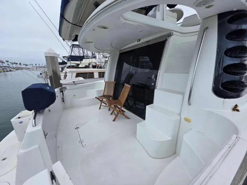 Slide: The Image of 2000 Carver 450 Voyager Pilothouse yacht with spacious deck and wooden chairs at marina. - 18