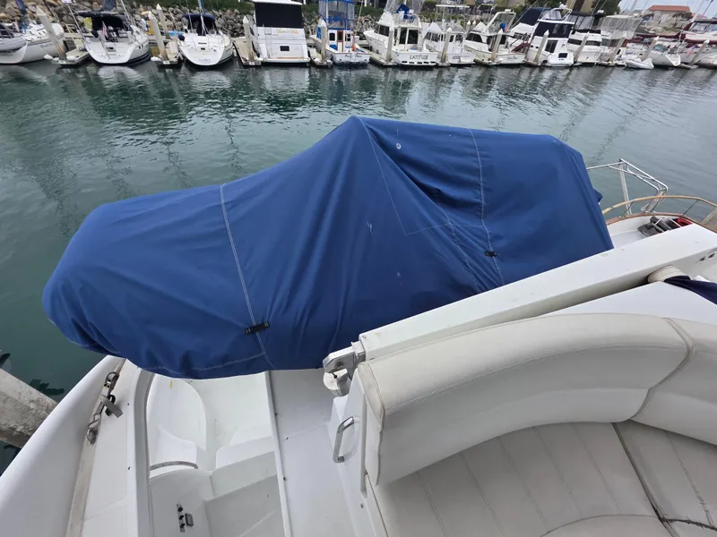 Slide: The Image of 2000 Carver 450 Voyager Pilothouse with blue cover docked at marina. - 35
