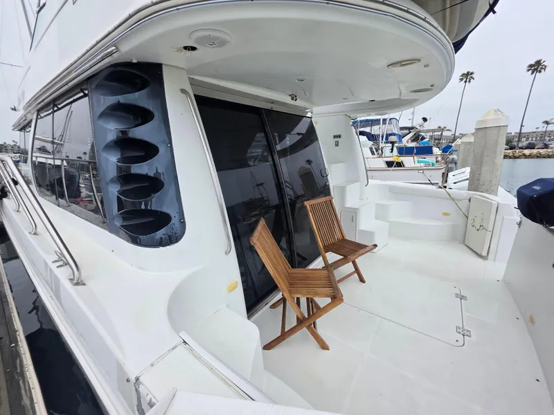 Slide: The Image of 2000 Carver 450 Voyager Pilothouse yacht with wooden chairs on deck, docked at marina. - 16