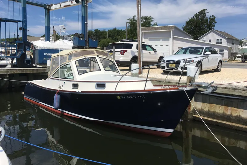 Slide: The Image of 2009 Landing School Arrundel 27 boat docked at a marina with cars in the background. - 28