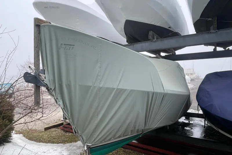 Slide: The Image of Covered 2009 Landing School Arundel 27 boat stored on a rack in a foggy setting. - 29