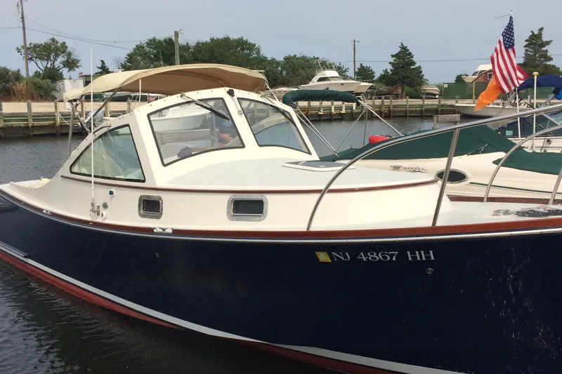 Slide: The Image of 2009 Landing School Arrundel 27 boat docked, featuring a navy hull and beige canopy. - 3