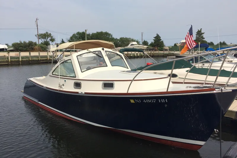 Slide: The Image of 2009 Landing School Arrundel 27 boat docked, featuring a sleek design and American flag. - 7