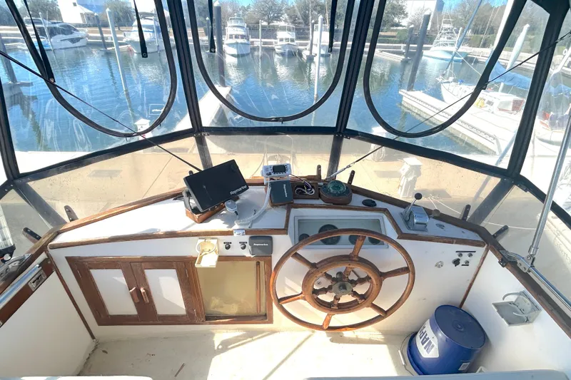 Slide: The Image of 1988 Grand Banks 36 Classic helm with wooden wheel, navigation equipment, and marina view. - 14