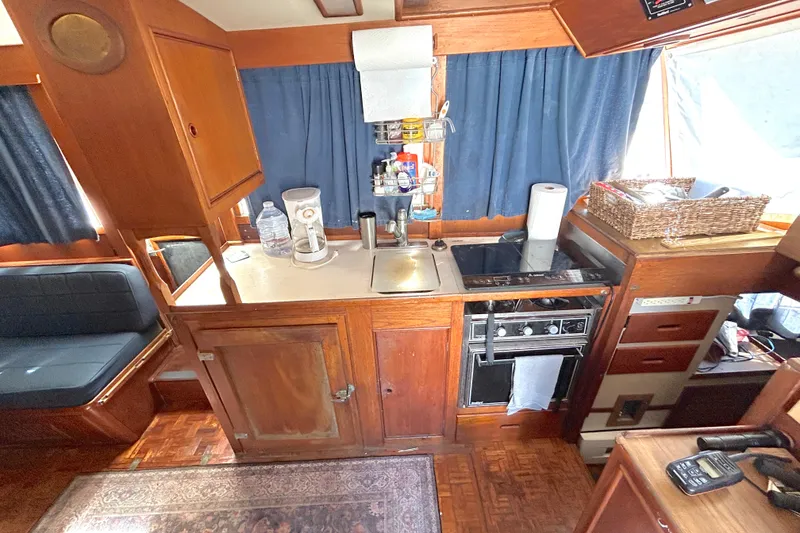 Slide: The Image of 1988 Grand Banks 36 Classic yacht interior kitchen with stove, sink, and wooden cabinetry. - 28
