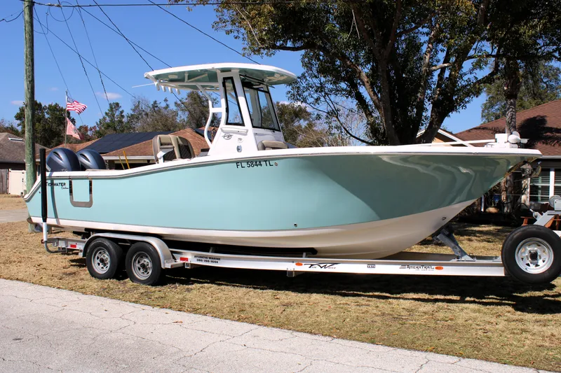 The Image of 2022 Tidewater 272 CC Adventure boat on trailer, parked in residential area. - 0