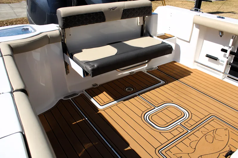 Slide: The Image of 2022 Tidewater 272 CC Adventure boat interior with cushioned seating and teak-style flooring. - 13