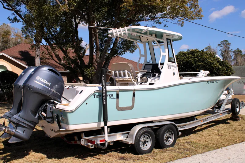 Slide: The Image of 2022 Tidewater 272 CC Adventure boat on trailer with Yamaha engines, parked outdoors. - 2