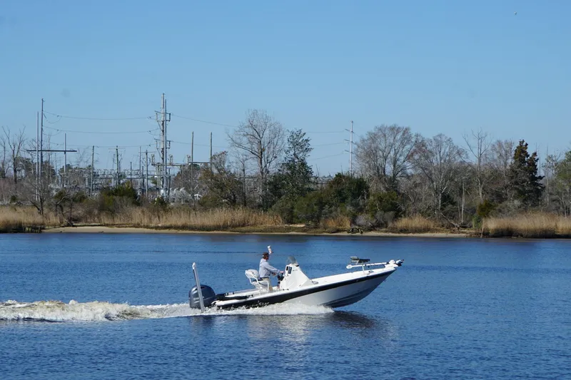 Slide: The Image of 2023 NauticStar 215 XTS boat cruising on a calm river with trees in the background. - 10