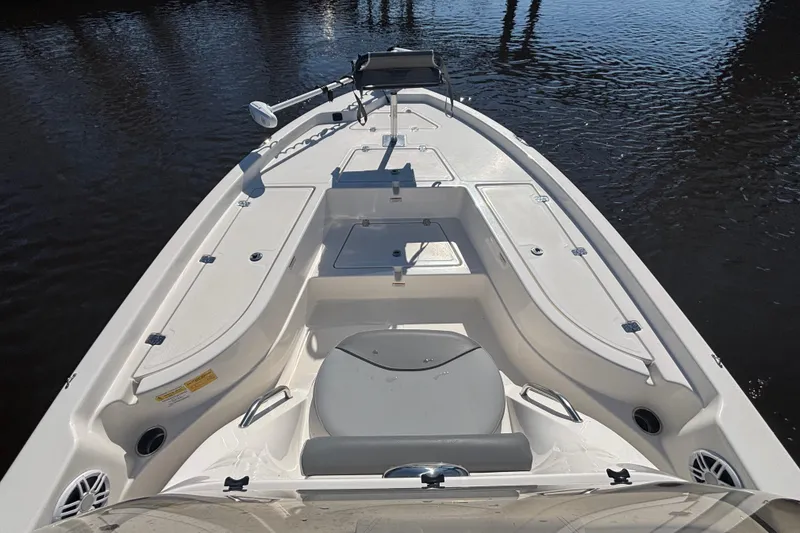 Slide: The Image of 2023 NauticStar 215 XTS boat deck with storage compartments on calm water. - 2