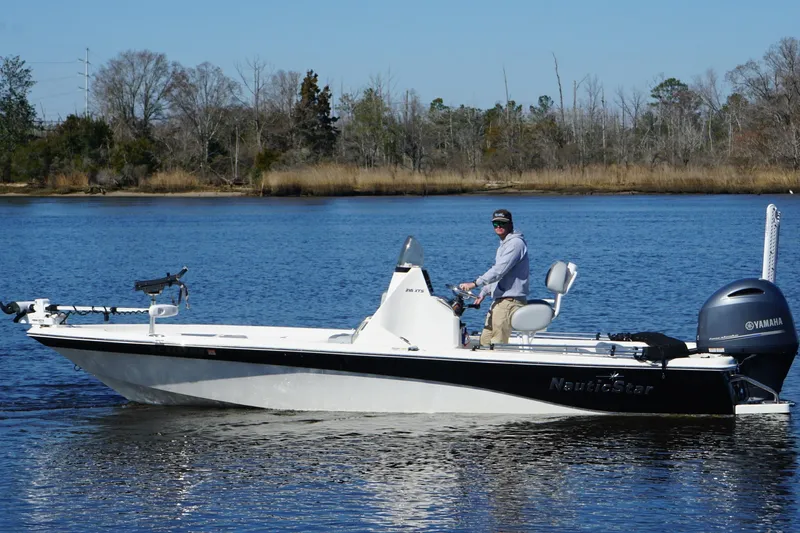 Slide: The Image of 2023 NauticStar 215 XTS boat on a calm lake with a person steering. - 7