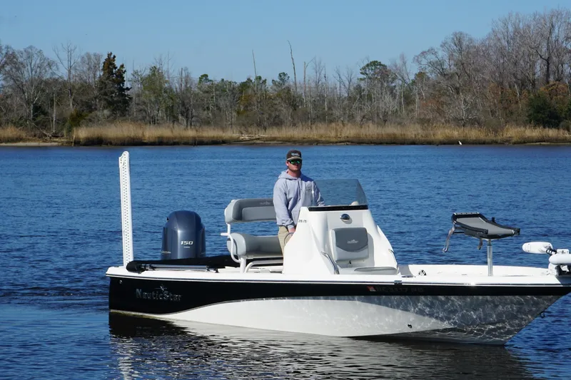 Slide: The Image of 2023 NauticStar 215 XTS boat on calm water with a person at the helm. - 9