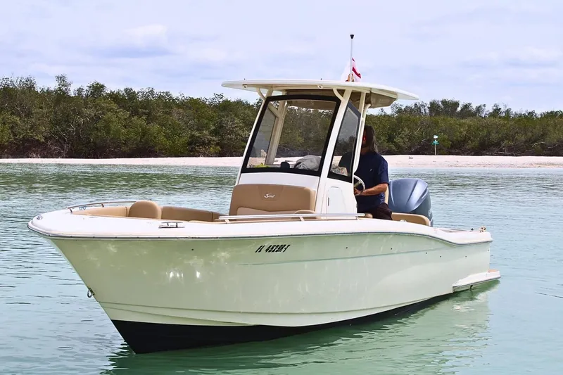 Slide: The Image of 2019 Scout 235 XSF boat on calm water near a sandy shore. - 4