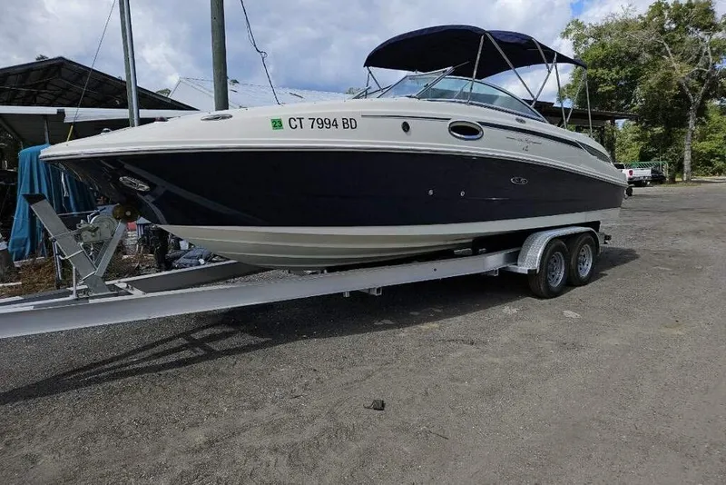 The Image of 2009 Searay 260 boat on trailer, parked outdoors under cloudy sky. - 1