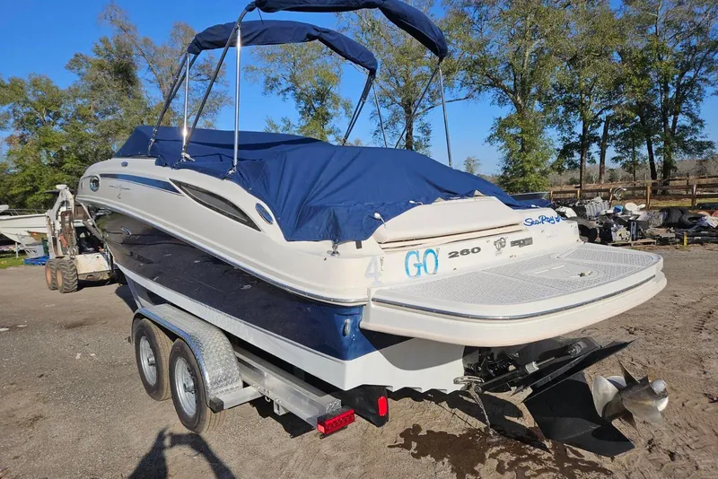 Slide: The Image of 2009 Searay 260 boat on trailer with blue cover, parked outdoors. - 5