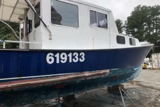 Slide: The Image of 1979 Bruno & Stillman 35 Downeast Cruiser on dry dock, blue hull, white cabin. - 2