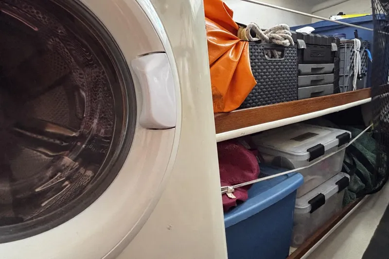 Slide: The Image of Storage area inside a 2005 Catalina Morgan 440 yacht with organized bins and a washing machine. - 18