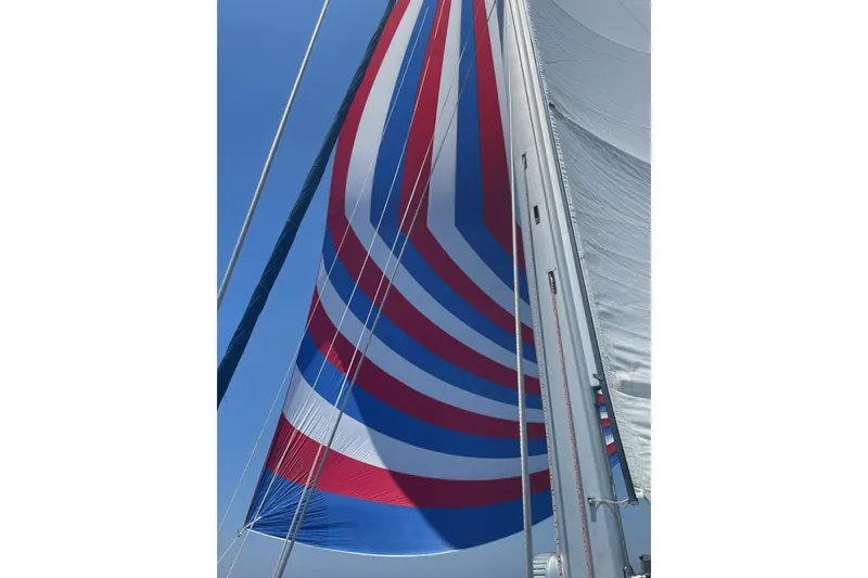 Slide: The Image of Sailboat with colorful spinnaker sail, Catalina Morgan 440, 2005 model, against clear blue sky. - 19