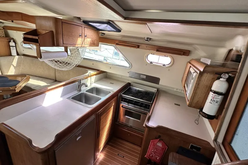 Slide: The Image of Interior of 2005 Catalina Morgan 440 yacht kitchen with stove, sink, and wooden cabinetry. - 24