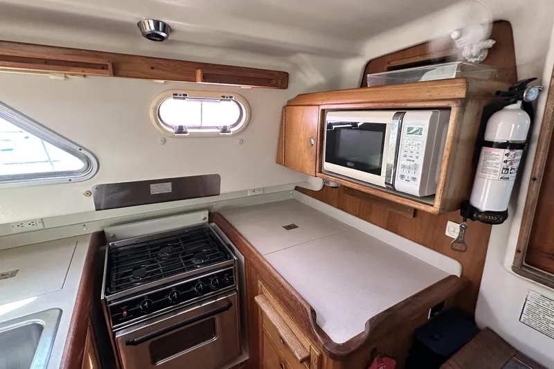 Slide: The Image of 2005 Catalina Morgan 440 yacht kitchen with stove, microwave, and fire extinguisher. - 26