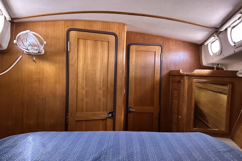 Slide: The Image of Interior cabin of 2005 Catalina Morgan 440 sailboat with wooden doors and blue bedding. - 34
