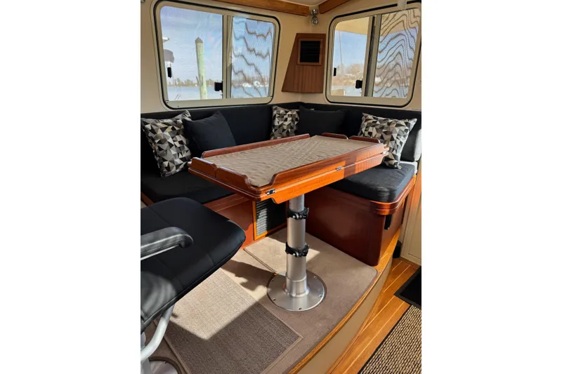 Slide: The Image of 2008 Island Packet SP Cruiser interior with cushioned seating and wooden table. - 13