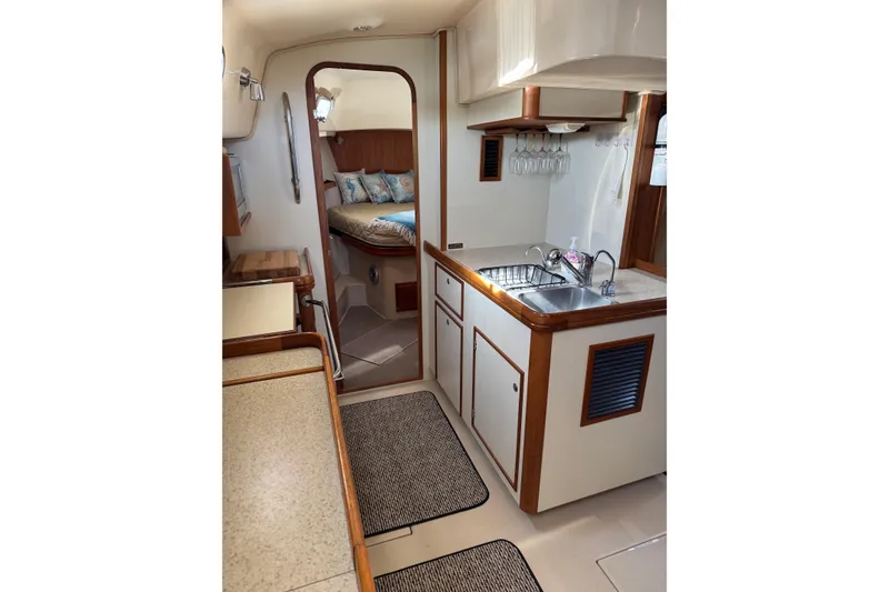 Slide: The Image of Interior of 2008 Island Packet SP Cruiser, featuring a compact kitchen and cozy sleeping area. - 8