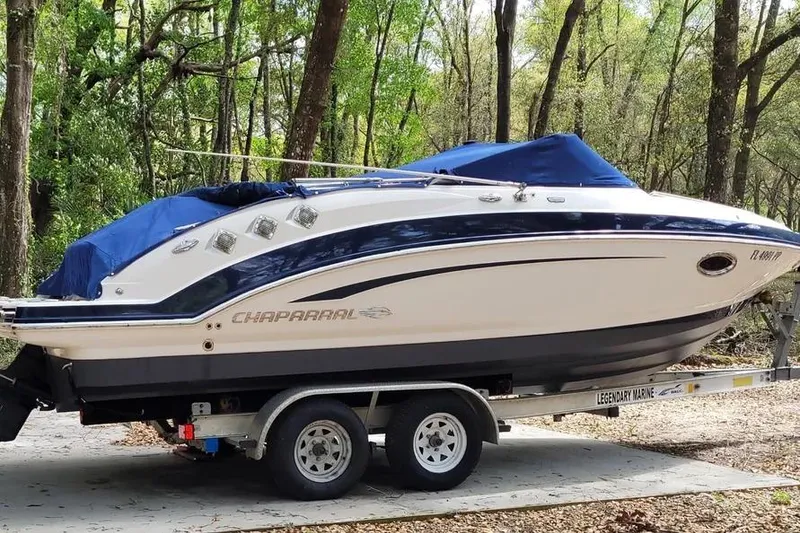 Slide: The Image of 2014 Chaparral 225 SSi boat on trailer, covered, in wooded area. - 1