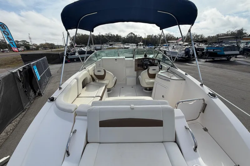 Slide: The Image of 2014 Chaparral 225 SSi boat interior with seating and canopy, docked outdoors. - 11