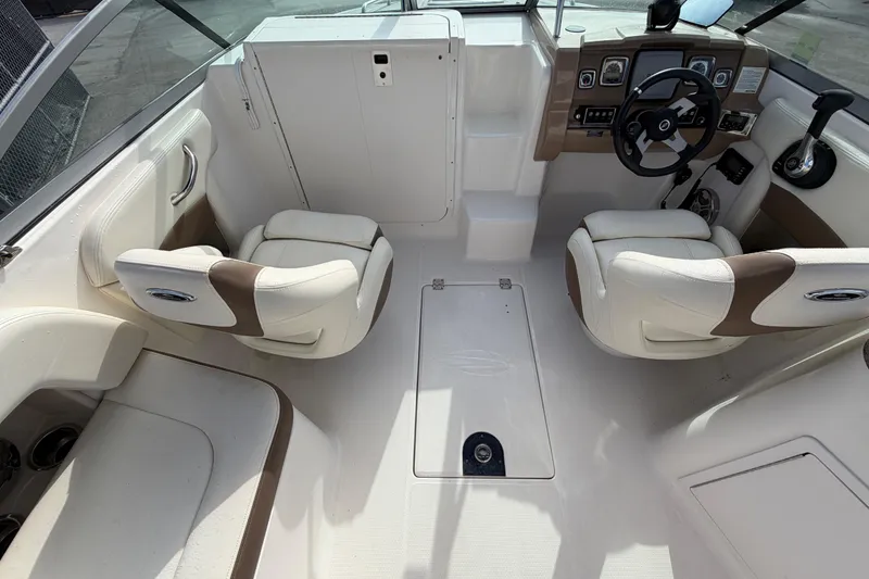 Slide: The Image of 2014 Chaparral 225 SSi boat interior with white and brown seating, steering wheel, and dashboard. - 15