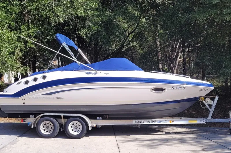 Slide: The Image of 2014 Chaparral 225 SSi boat on trailer, blue and white design, parked outdoors. - 2