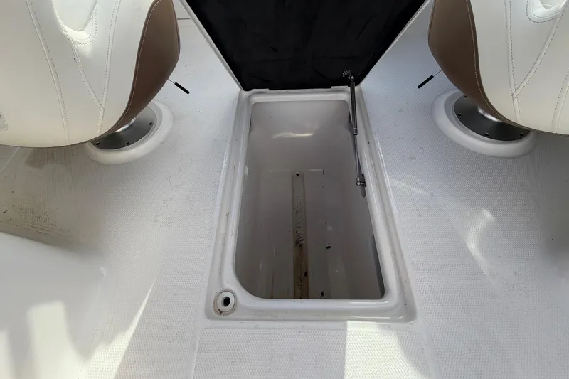 Slide: The Image of Open storage compartment on 2014 Chaparral 225 SSi boat, between two seats. - 22