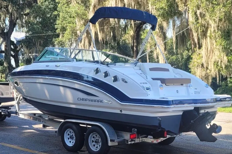 Slide: The Image of 2014 Chaparral 225 SSi boat on trailer, parked outdoors with trees in background. - 3