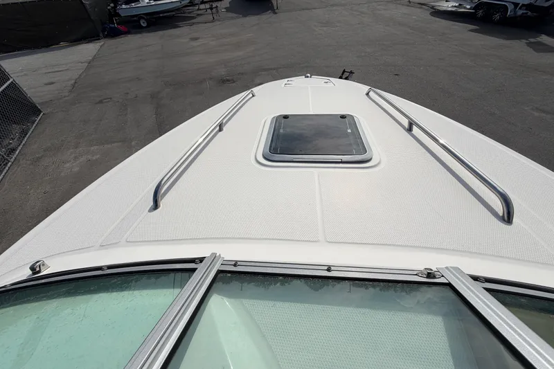 Slide: The Image of 2014 Chaparral 225 SSi boat deck with hatch and railings, parked on asphalt. - 36