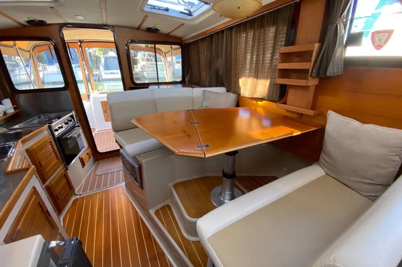 Slide: The Image of 2013 Ranger Tugs R-29 S interior with dining area and kitchen, featuring wood accents. - 19