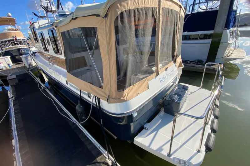 Slide: The Image of 2013 Ranger Tugs R-29 S docked, featuring a covered rear deck and sleek design. - 5