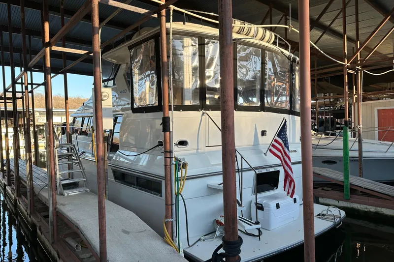 Slide: The Image of 1995 Carver 440 Aft Cabin Motor Yacht docked with American flag displayed. - 4
