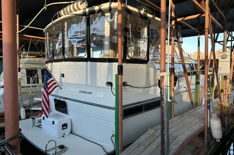 Slide: The Image of 1995 Carver 440 Aft Cabin Motor Yacht docked with American flag displayed. - 3