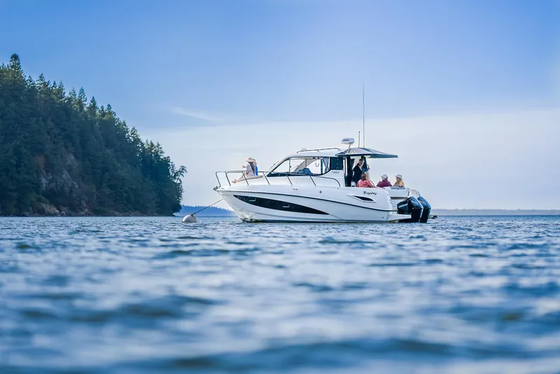 Slide: The Image of 2026 Trophy T29EX Explorer boat cruising near forested shoreline. - 20