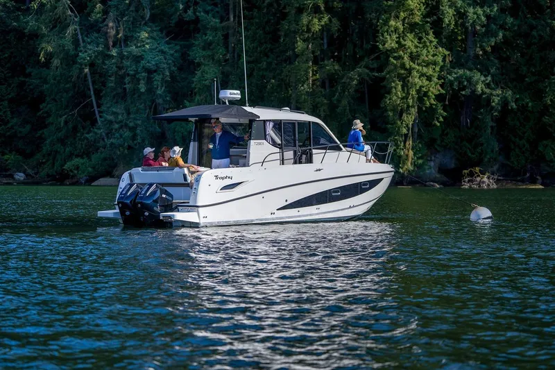 Slide: The Image of 2026 Trophy T29EX Explorer boat cruising on a serene lake with lush forest backdrop. - 21