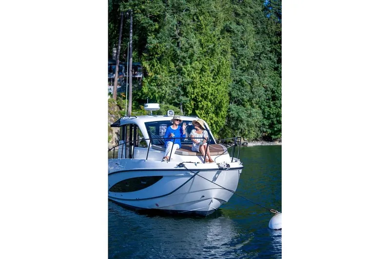 Slide: The Image of Two people relaxing on a 2026 Trophy T29EX Explorer boat by a forested shoreline. - 22