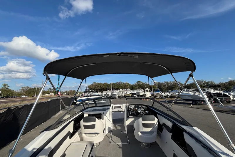 Slide: The Image of 2022 Yamaha Boats SX195 with canopy, parked in a marina under a clear blue sky. - 16