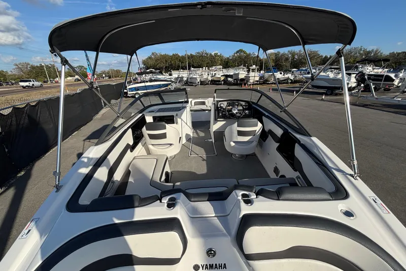 Slide: The Image of 2022 Yamaha Boats SX195 interior with seating and canopy, parked at a marina. - 17