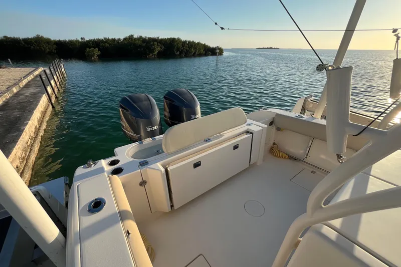 Slide: The Image of 2014 Cobia 296 Center Console boat with dual engines, docked by serene waters. - 10
