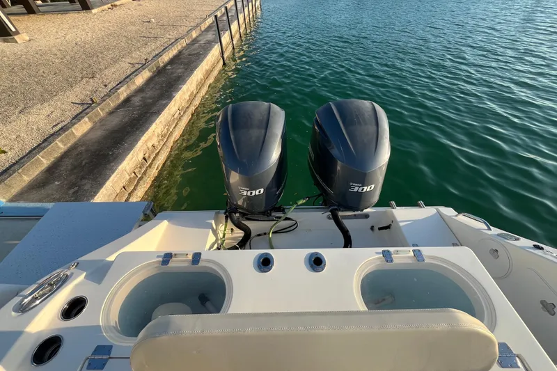 Slide: The Image of 2014 Cobia 296 Center Console with twin Yamaha 300 engines docked by the water. - 12