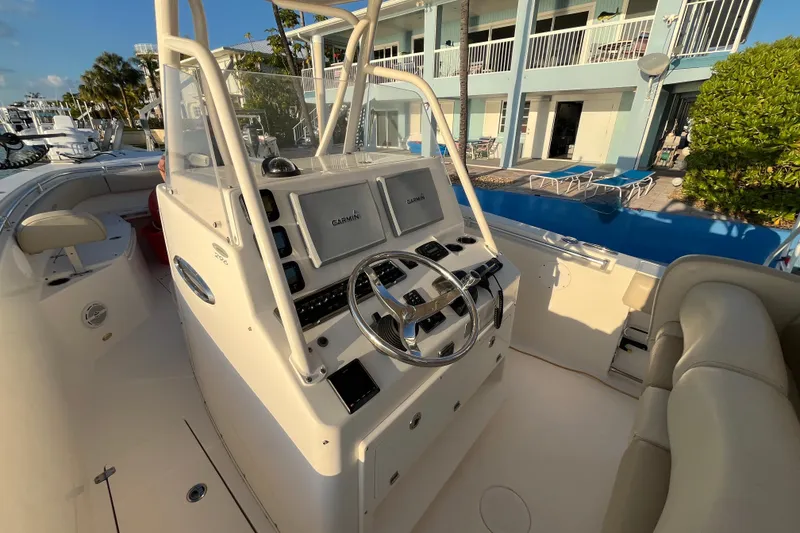 Slide: The Image of 2014 Cobia 296 Center Console boat with Garmin navigation, docked near a waterfront building. - 6