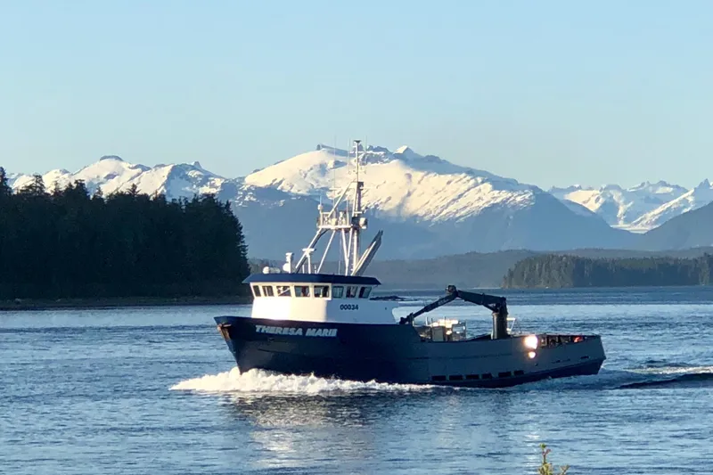 Slide: The Image of Custom 1974 Steel Cannery Tender boat cruising with snowy mountains in the background. - 1