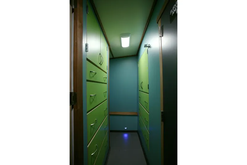 Slide: The Image of Narrow hallway with green cabinets inside a 1974 Custom Steel Cannery Tender. - 12
